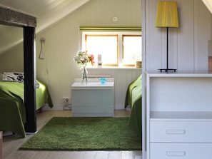 A bedroom with two beds, a small desk with a vase of flowers, a lamp, and a window with a view. - 6 Person Holiday Home in Stjarnhov (Stjarnhov)