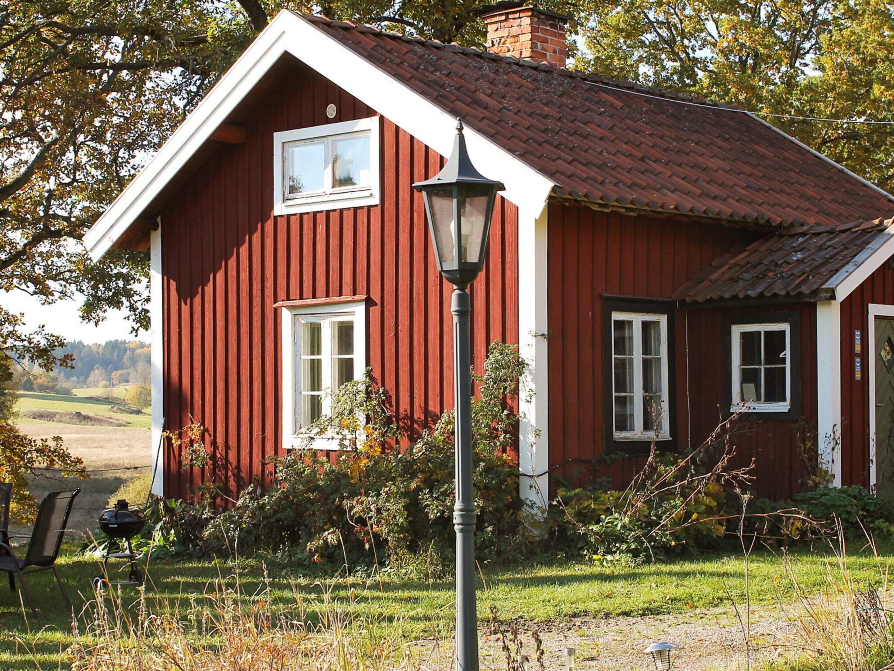 A red wooden house with white trim, a chimney, and a window.