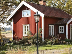 A red wooden house with white trim, a chimney, and a window. - 6 Person Holiday Home in Stjarnhov (Stjarnhov)