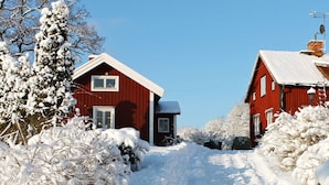 A snow-covered path leading to a red wooden house with a white window and door. - 6 Person Holiday Home in Stjarnhov (Stjarnhov)