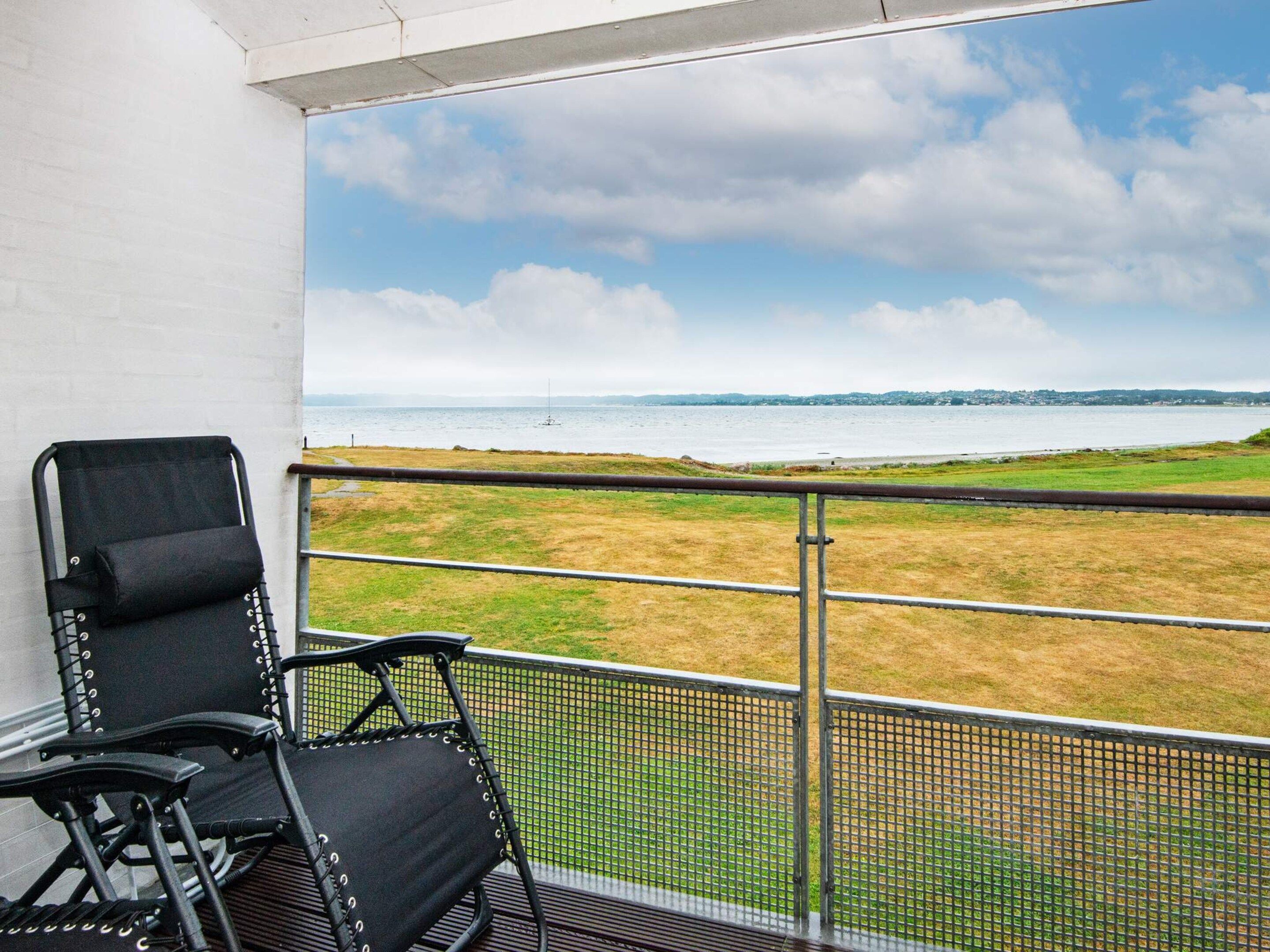A balcony with a view of a grassy field and a body of water.