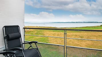 A balcony with a view of a grassy field and a body of water.