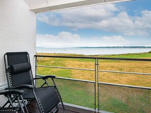 A balcony with a view of a grassy field and a body of water. - 6 Person Holiday Home in Ebeltoft (Ebeltoft)
