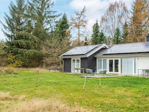 A modern house with solar panels, a patio with chairs, and a grassy yard. - 6 Person Holiday Home in Silkeborg (Silkeborg)