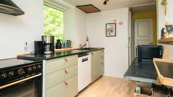 A compact kitchen with a stove, oven, and coffee maker.