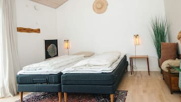 A bedroom with a double bed, two bedside tables, a floor lamp, a chair, a potted plant, and a large rug.