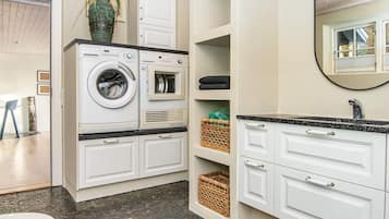 A compact laundry room with a washing machine, dryer, and storage shelves.