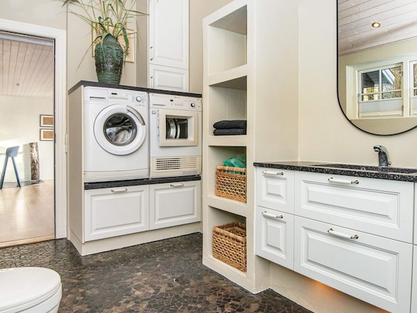 Une petite buanderie équipée d’un lave-linge, d’un sèche-linge et d’étagères de rangement.
