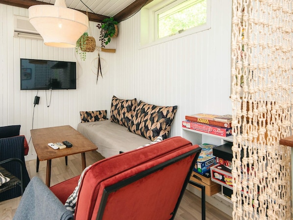 A cozy room with a sofa, a TV mounted on the wall, and a table with board games.