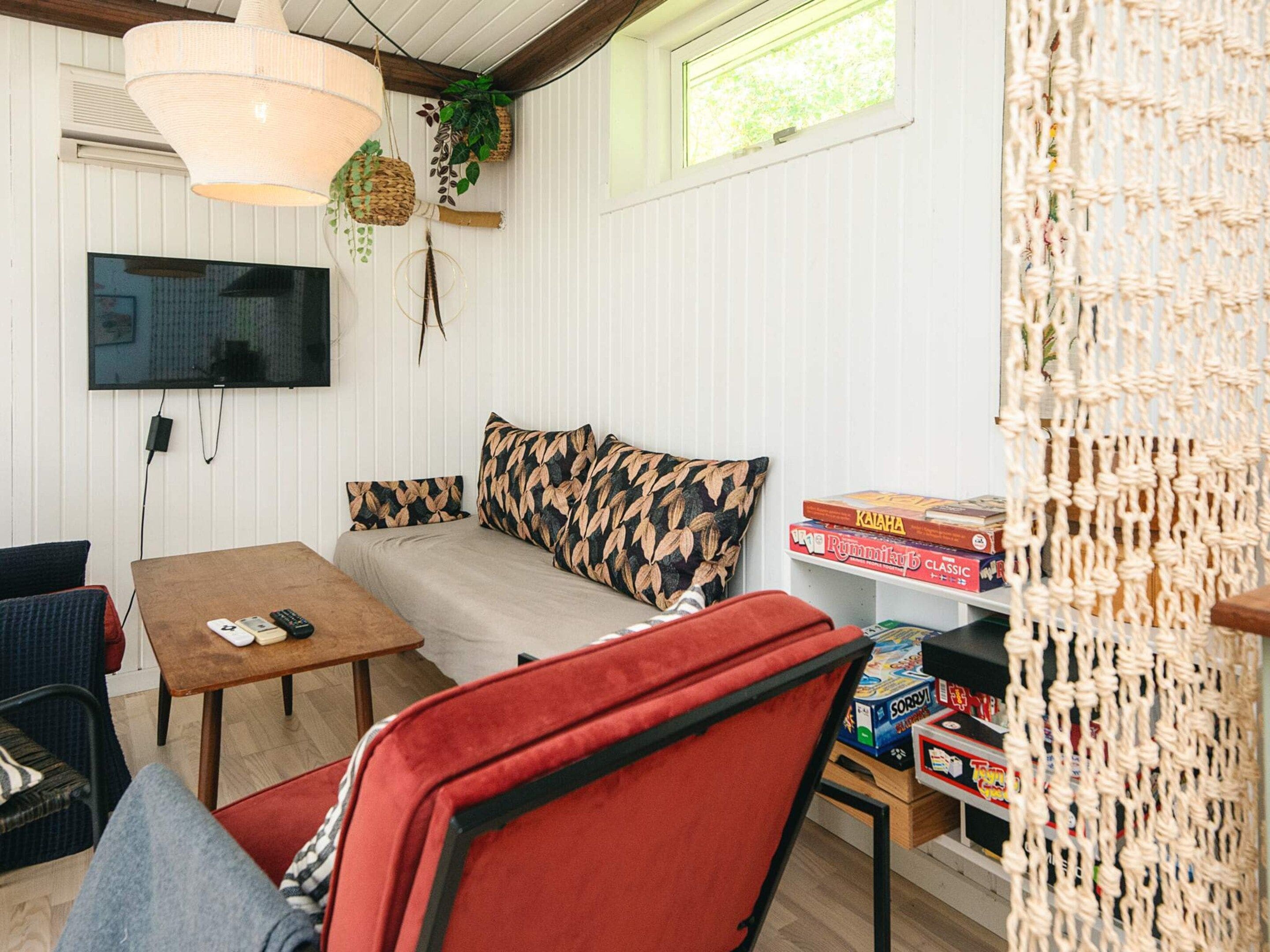 Una habitación acogedora con sofá, una mesita de centro, televisor montado en la pared y ventana con vistas.