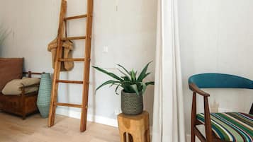 A room with a wooden ladder, a potted plant, a striped chair, and a wooden stool.