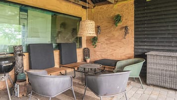 An outdoor seating area with chairs and tables, a hanging light fixture, and a potted plant.
