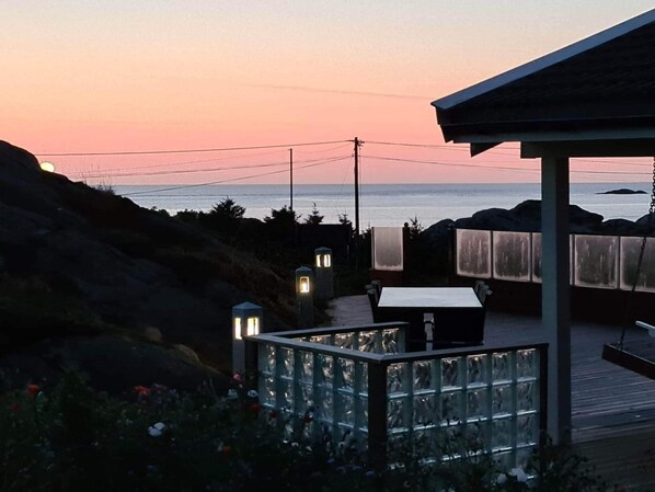 A coastal outdoor seating area with a view of the ocean at sunset. - 4 Star Holiday Home in Skudeneshavn (Karmoy)