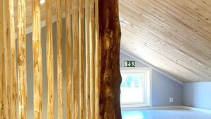 Un intérieur spacieux avec un plafond haut et un grand tronc d’arbre en bois qui domine le premier plan.