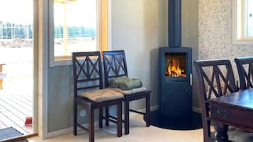 Una habitación con chimenea, sillas de madera, una mesa de comedor y vistas a través de una ventana.