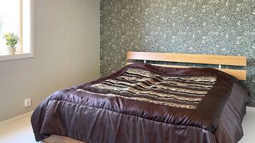 Quarto com uma cama, janela e parede com padrão floral.