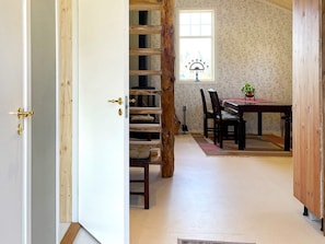 A room with a wooden staircase, a dining table with chairs, and a window with a plant on it. - 4 Star Holiday Home in Sandhem (Sandhem)