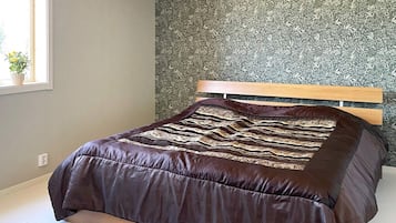 A bedroom with a bed, a window, and a wall with a floral pattern.