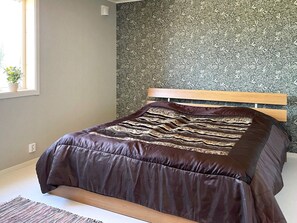 A bedroom with a bed, a window, and a wall with a floral pattern. - 4 Star Holiday Home in Sandhem (Sandhem)