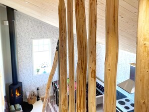 A room with a wooden ceiling, a fireplace, a window, and a stove. - 4 Star Holiday Home in Sandhem (Sandhem)