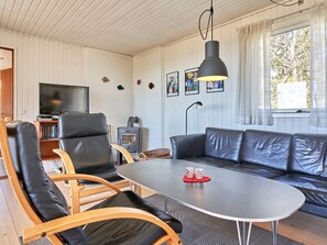 Uma sala de estar aconchegante com sofá, poltronas, TV e lareira.