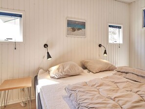 Quarto com cama, duas luminárias de cabeceira, pintura de céu noturno e janela com persianas.