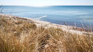 A beach with clear water, grassy dunes, and a clear sky. - 6 Person Holiday Home in Aakirkeby (Akirkeby)