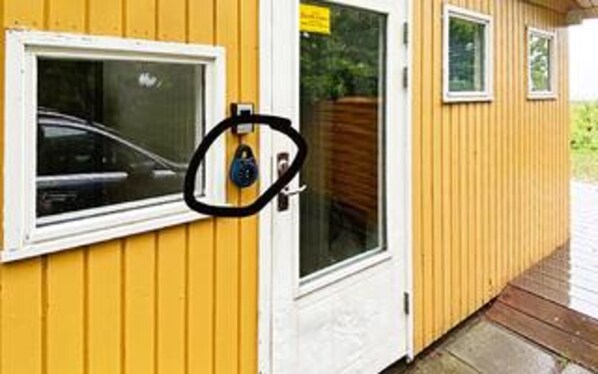 A yellow building with a window, a door, and a small window above the door.