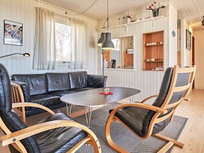 A cozy living room with a leather sofa, wooden chairs, a round table, and a hanging lamp. - 6 Person Holiday Home in Aakirkeby (Akirkeby)