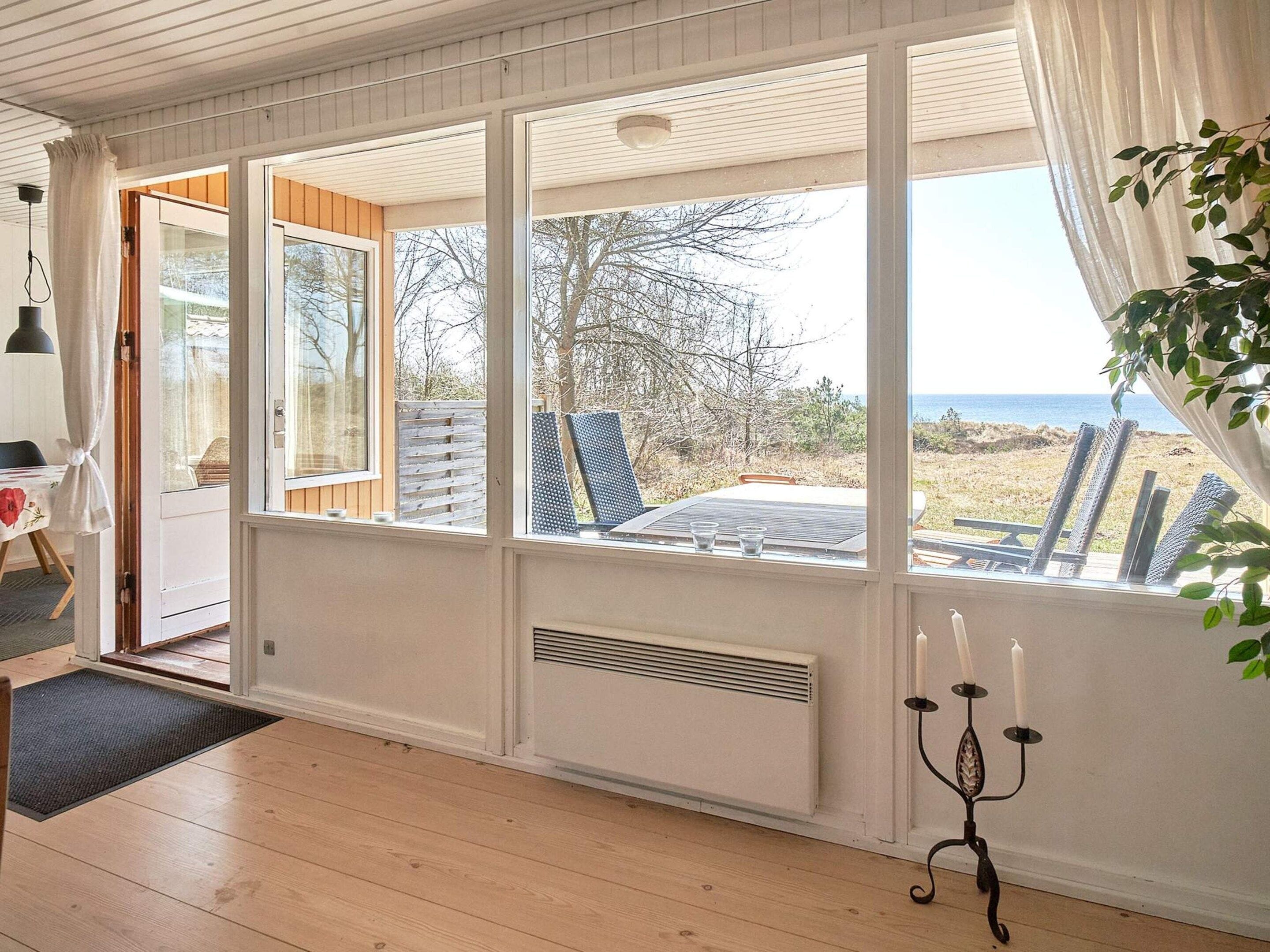Ein Zimmer mit großem Fenster, Heizkörper, einem Kandelaber und Blick ins Freie.