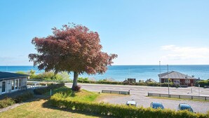 Ein Küsteneigentum mit einem großen Baum, einem Parkplatz und Meerblick.