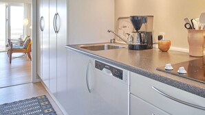 Eine moderne Küche mit weißen Schränken, einer Kaffeemaschine und einem Spülbecken.