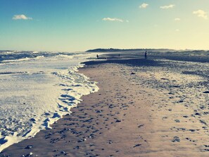A beach with footprints and waves.