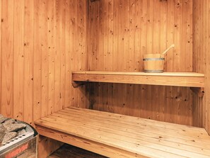 A wooden sauna with a bench and a bucket.