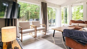 A modern living room with a flat-screen TV, a sofa, a coffee table, and a dining area with chairs and a table. - 10 Person Holiday Home in Fjerritslev (Fjerritslev)