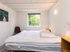 A bedroom with a bed, a chair, a window, and a painting on the wall.