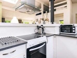 A modern kitchen with a built-in oven, a microwave, and a kettle on the countertop.