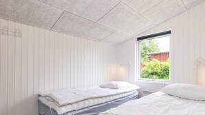 A room with two beds, a window with a view of greenery, and a white ceiling. - 10 Person Holiday Home in Fjerritslev (Fjerritslev)