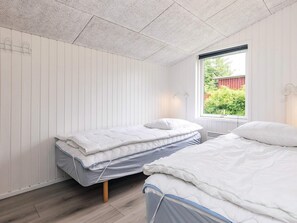 Una habitación con dos camas, una ventana que da a zonas verdes y un techo blanco.
