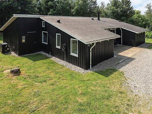 A black metal building with a gravel driveway and a grassy area.
