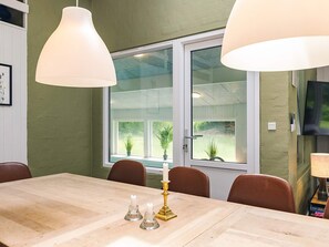 A dining area with a wooden table, brown chairs, a candle holder, and pendant lights.