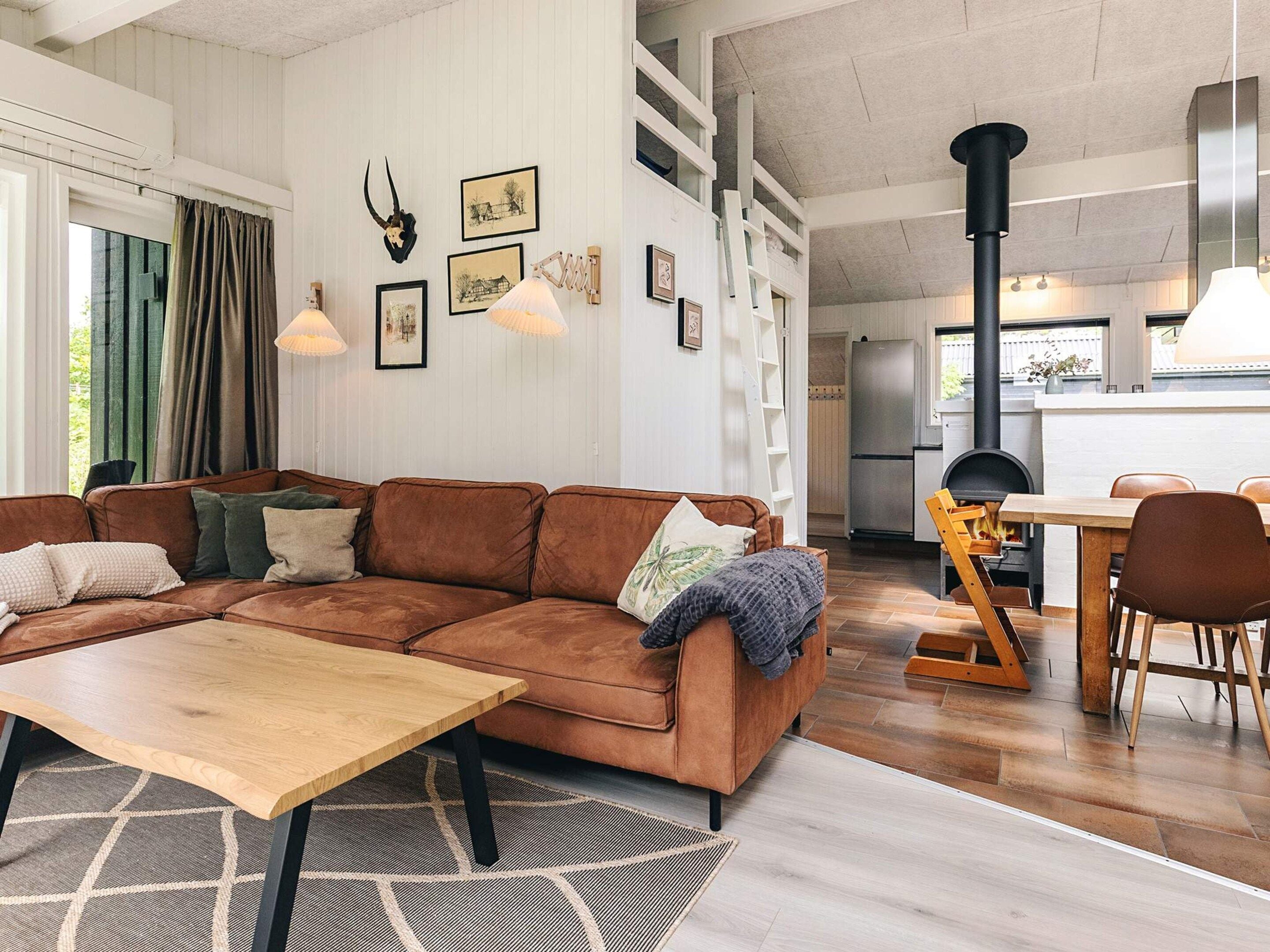 A modern living room with a brown sectional sofa, a wooden coffee table, and a dining area with a wooden table and chairs.