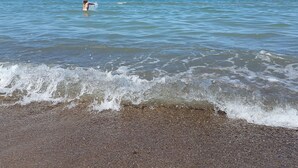 A beach with waves, a person in the water, and a clear sky. - 10 Person Holiday Home in Fjerritslev (Fjerritslev)