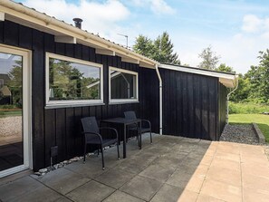 A black building with two windows and a patio area with two chairs. - 10 Person Holiday Home in Fjerritslev (Fjerritslev)