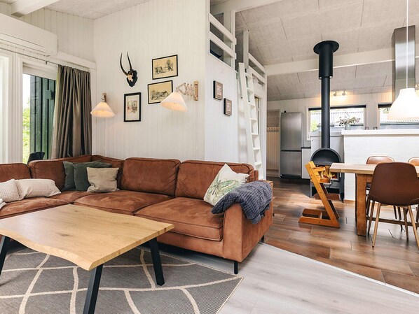 A modern living room with a brown sectional sofa, a wooden coffee table, and a dining area with a wooden table and chairs.