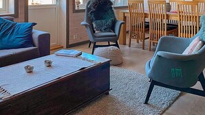 A modern living room with a sofa, armchair, and coffee table. There is a dining area with wooden chairs and a table. - 10 Person Holiday Home in Rauland (Vinje)
