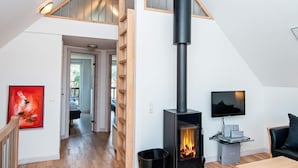 Ein modernes Interieur mit einer Holztreppe, einem Kamin, einem Fernseher und einem Essbereich.