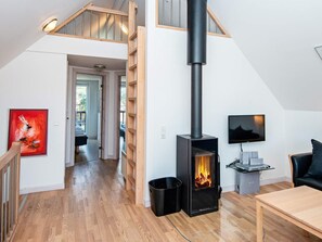 A modern interior with a wooden staircase, a fireplace, a television, and a dining area. - 8 Person Holiday Home in Romo (Rømø)