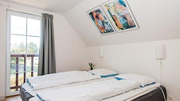 A bedroom with a bed, a window with curtains, and two wall-mounted light fixtures.