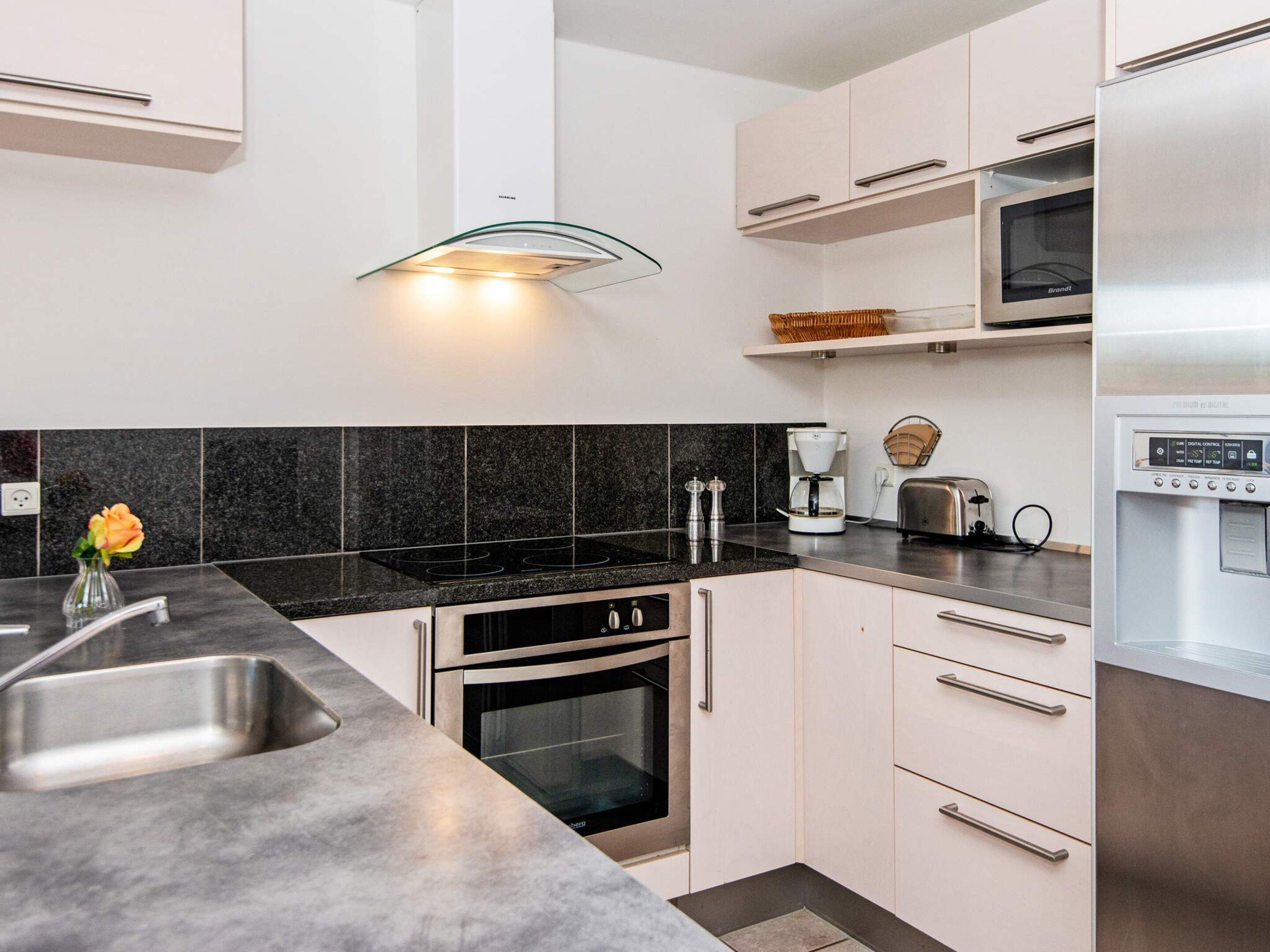 Una cocina moderna con refrigerador de acero inoxidable, horno doble y microondas integrado.